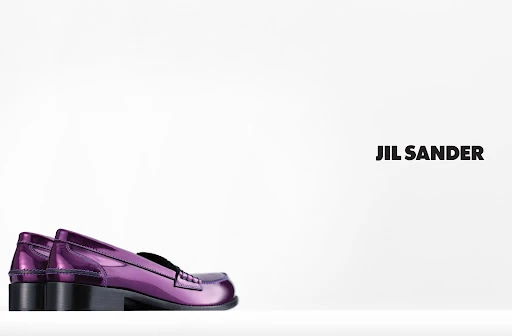 Studio shot of shiny purple Jil Sander penny loafers on a white surface with a bright white background and clear Jil Sander branding.