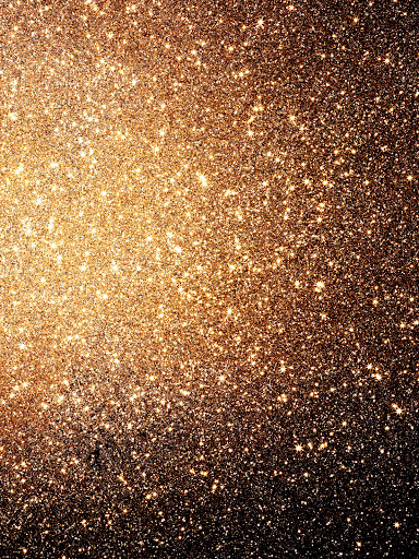 Abstract close-up of glistening, blurred, golden glitter with bokeh effect against a dark background, creating a sparkling, festive texture.