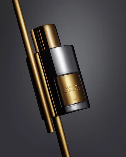 Elegant studio shot of a gold and silver perfume bottle with metallic accents on a gray backdrop, creating a sophisticated beauty aesthetic.
