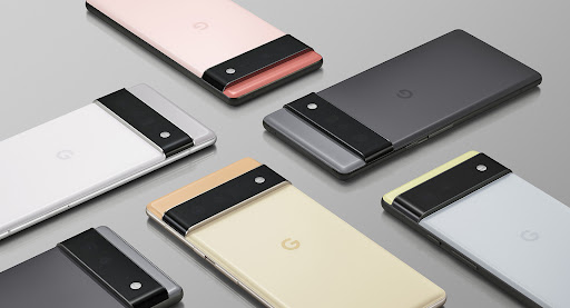 A group of Google Pixel 6 smartphones in various colors are arranged on a light gray surface, showcasing their design.