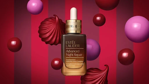 Estee Lauder Advanced Night Repair serum with a dropper, presented against a bold red and pink striped background with floating spheres.