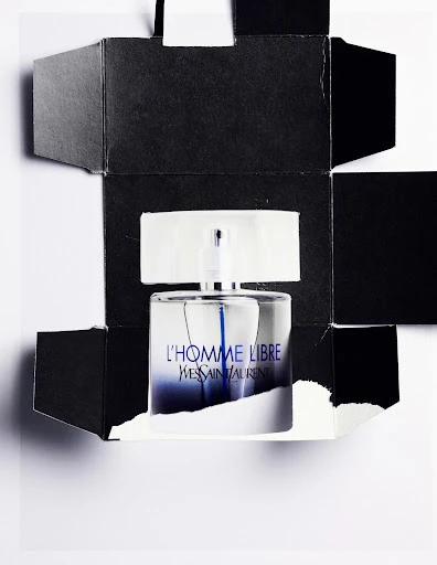 A sleek perfume bottle encased in a deconstructed black box against a white background, highlighting its gradient blue label and minimalist design.