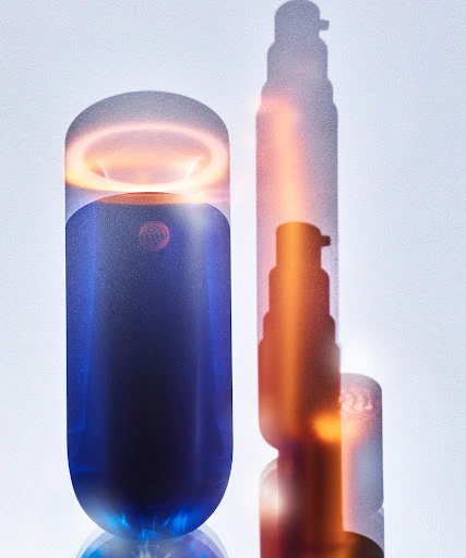 Product shot of a blue and clear cosmetic bottle with a pump shadow, showcasing modern beauty and skincare product design.