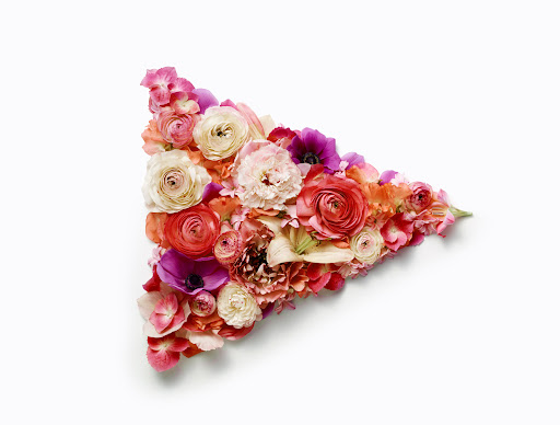 Floral arrangement of roses, anemones, and hydrangeas in a triangular shape on a white background. Perfect for Valentine's Day or spring.