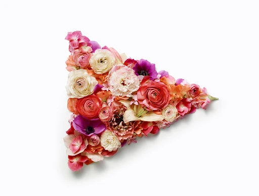 Floral arrangement of roses, anemones, and hydrangeas in a triangular shape on a white background. Perfect for Valentine's Day or spring.
