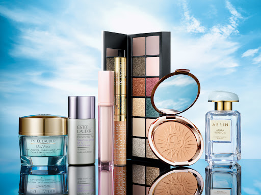 Assortment of Estee Lauder and Aerin beauty products including moisturizer, serum, concealer, eye shadow, face powder, and perfume.