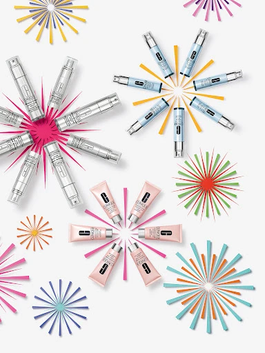 Eye and lip beauty product tubes arranged in starburst shapes against a white backdrop with colorful starbursts in a studio shot.