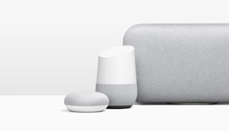 Three light grey fabric smart speakers arranged on a plain white surface against a white background