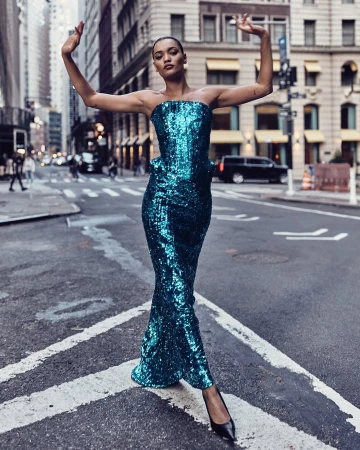 Model in a sparkling turquoise sequin strapless dress posing on a city street crossing by Billy Kidd