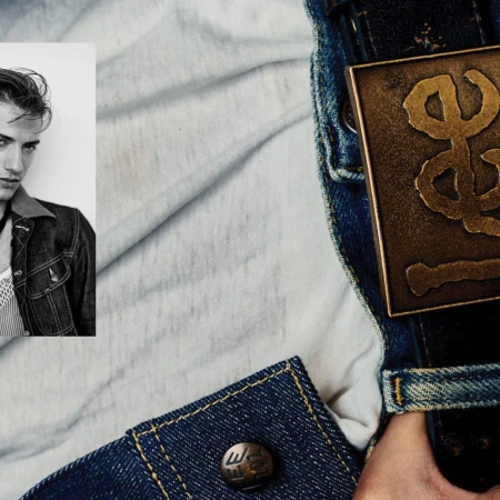 Close-up fashion shot: adult male poses in black and white photo booth-style portrait, wears denim jacket against a washed-out backdrop.