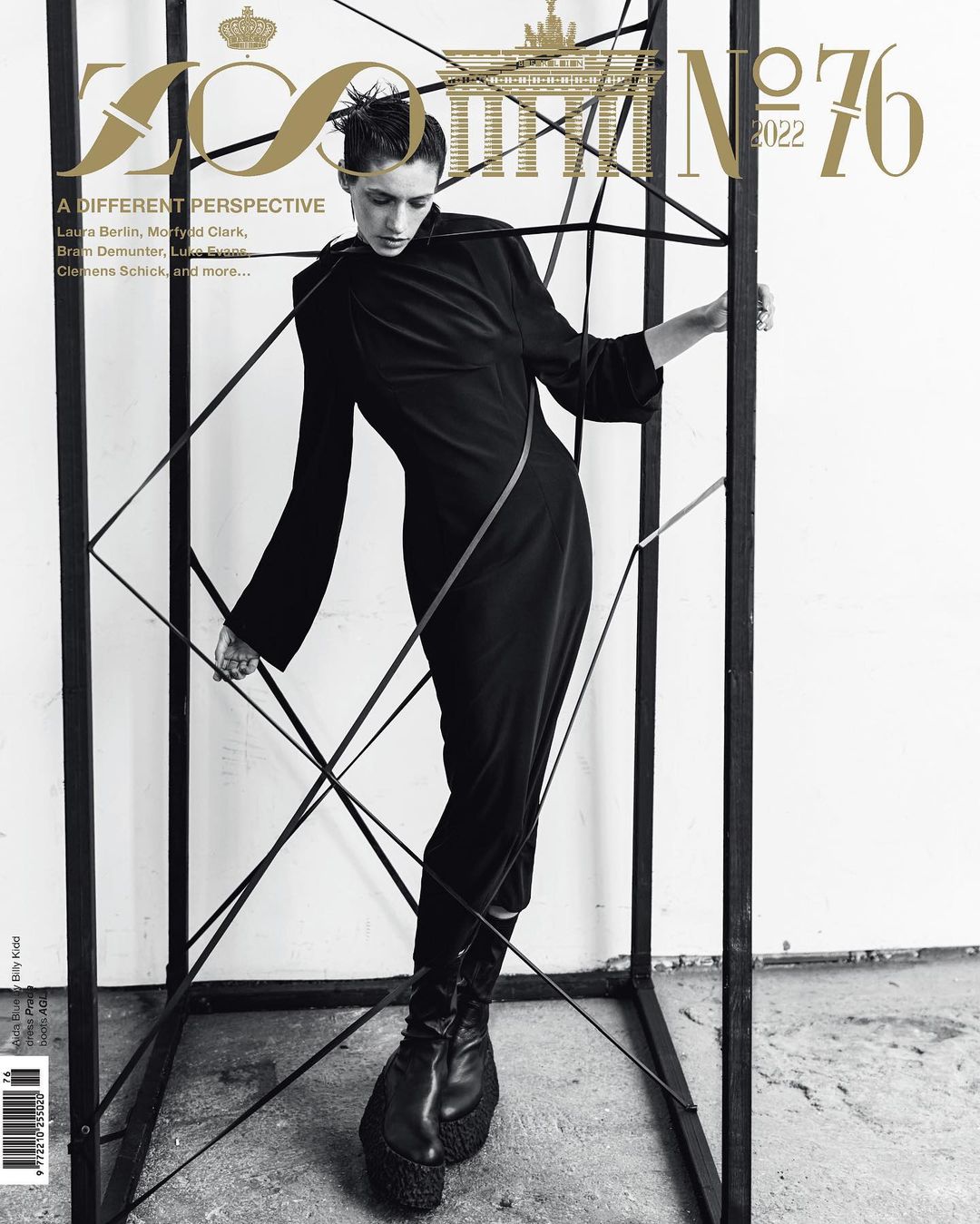 Fashion magazine cover featuring a slender female model in a black dress, posing within a black cube structure against a neutral backdrop.