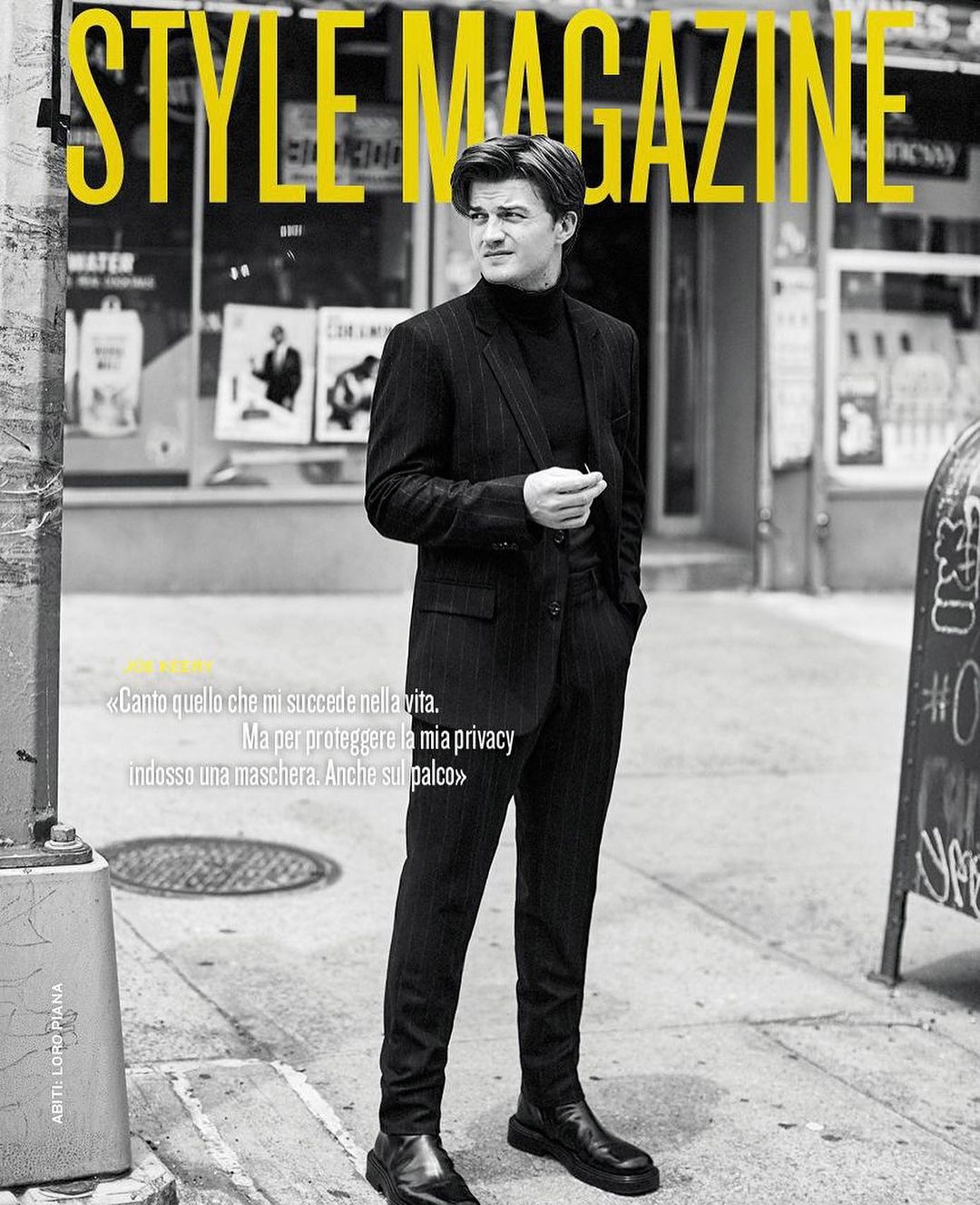 Black and white portrait of a man in a pinstripe suit and turtleneck standing on a city sidewalk by photographer Billy Kidd.