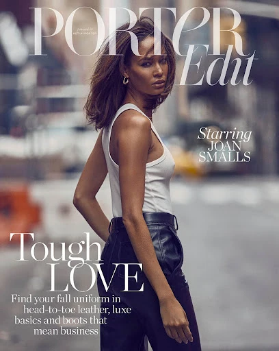 Magazine cover featuring Joan Smalls wearing a white tank top and leather pants, set against a blurred urban street backdrop.