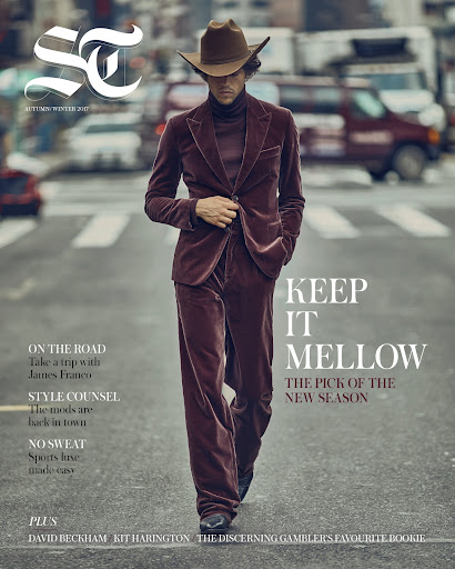 Magazine cover featuring a stylish man in a brown velvet suit and cowboy hat walking on a city street, with cars in the background.