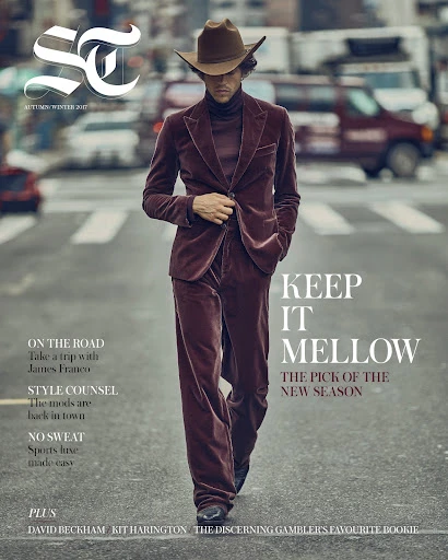 Magazine cover featuring a stylish man in a brown velvet suit and cowboy hat walking on a city street, with cars in the background.