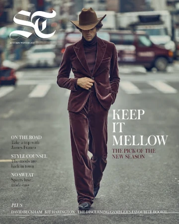 Magazine cover featuring a stylish man in a brown velvet suit and cowboy hat walking on a city street, with cars in the background.