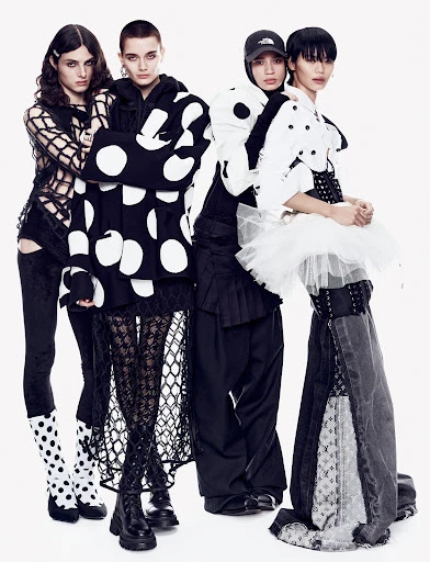 Four fashion models in black and white patterned clothing strike a pose in a studio setting, showcasing unique designs and style.