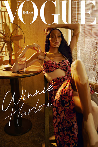 Vogue India cover featuring Winnie Harlow sitting in a chair, wearing a floral outfit. A vintage fan and a drink are visible.