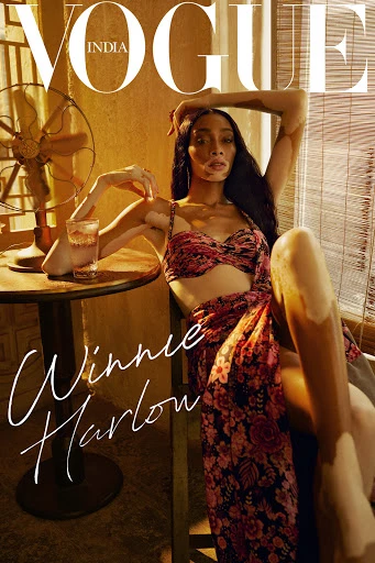 Vogue India cover featuring Winnie Harlow sitting in a chair, wearing a floral outfit. A vintage fan and a drink are visible.