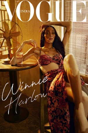 Vogue India cover featuring Winnie Harlow sitting in a chair, wearing a floral outfit. A vintage fan and a drink are visible.