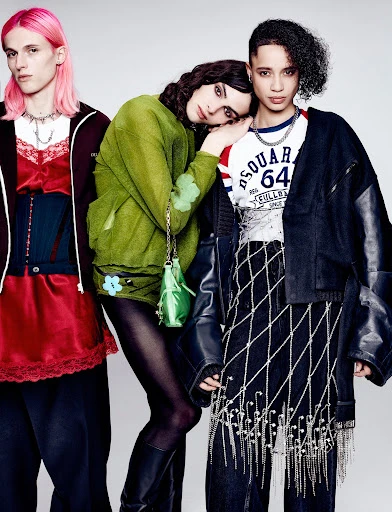 Three fashion models pose in a studio setting with diverse, colorful, and edgy clothing and accessories. Neutral backdrop.