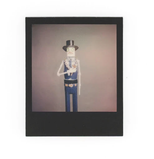 Stylized figure of a human skeleton in formal wear, including a top hat, vest, and belt, all rendered in a muted color palette.