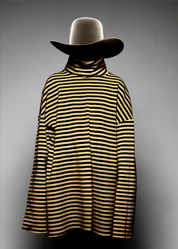 A striped sweater and hat are displayed on a mannequin against a grey background. The presentation highlights fashion apparel.