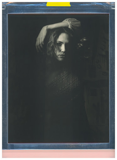 A vintage-style portrait of a woman with wavy hair, soft lighting, and a dark background, evoking a classic and artistic feel.
