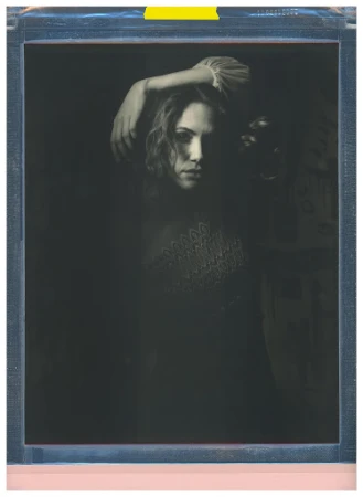 A vintage-style portrait of a woman with wavy hair, soft lighting, and a dark background, evoking a classic and artistic feel.