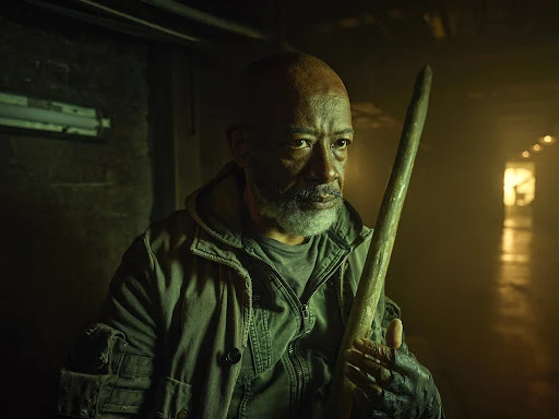 Portrait of an elderly African-American man in a gritty setting, wearing a green jacket, holding a wooden stick in a dimly lit corridor.