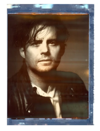 Polaroid portrait of a man with dark hair wearing a dark jacket, captured by photographer Brendan Meadows.