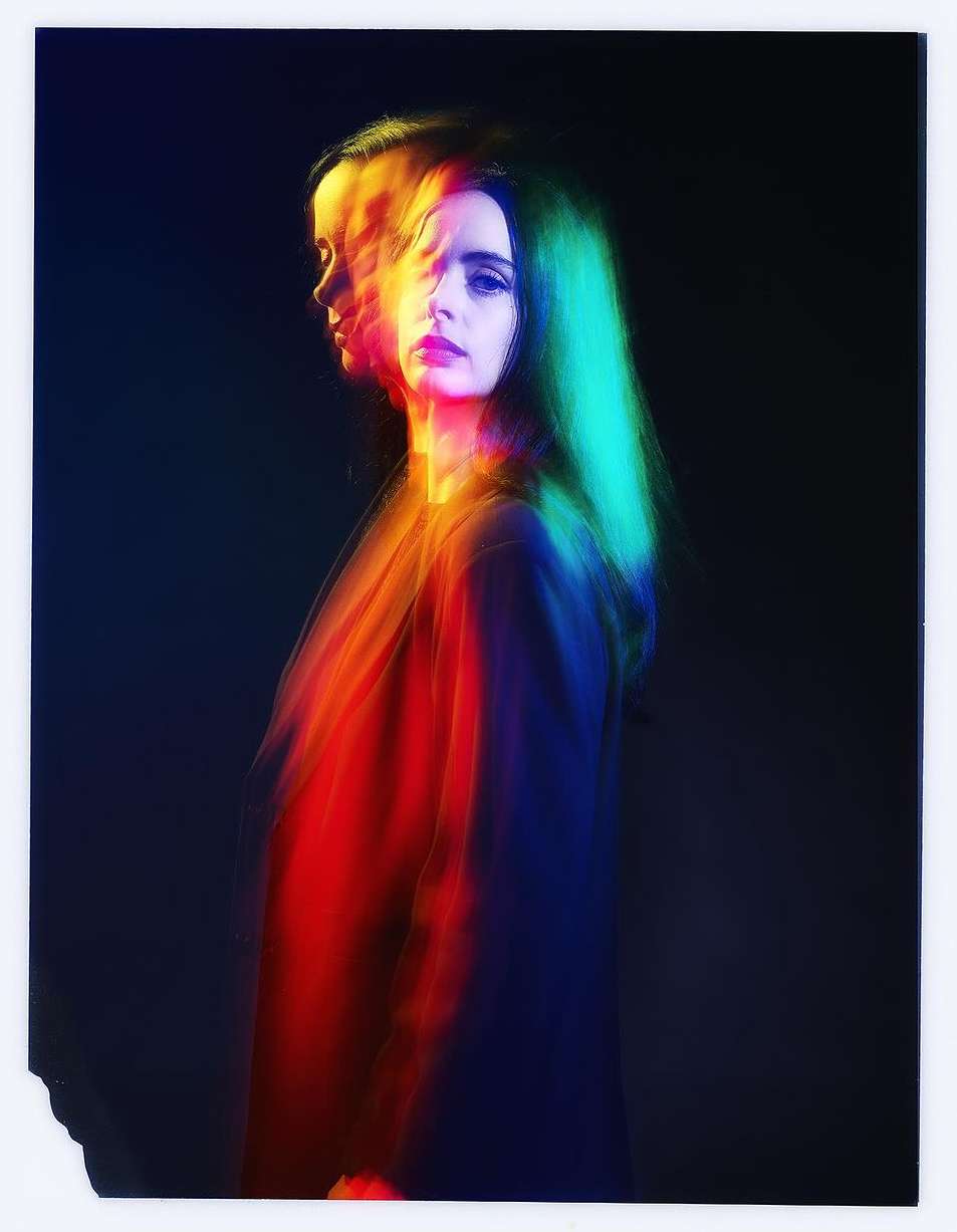 Portrait of a woman with long hair, in motion with blurred color layers. Dark background, studio lighting, and a moody atmosphere.