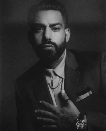 Portrait of a man in a tailored dark suit and button-down shirt, captured in a moody monochrome style by Brendan Meadows.
