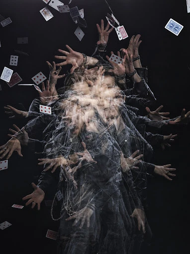 Multiple exposure effect: A person is tossing playing cards against a dark backdrop, creating a dynamic visual with blurry motion.