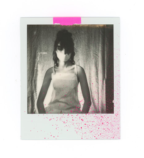 Polaroid photograph of a woman wearing a light strap top against a textured fabric curtain with pink paint splatter.