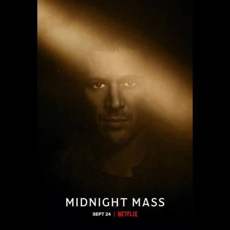 Headshot of a man with light shining on his face, dark hair, and some stubble, poster for Midnight Mass on Netflix, Sept 24th.
