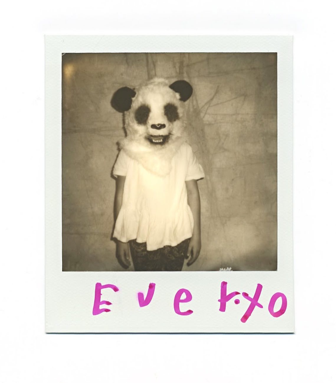 Person in a panda mask and white shirt, with pink handwritten text on a white background, evokes a surreal and vintage aesthetic.