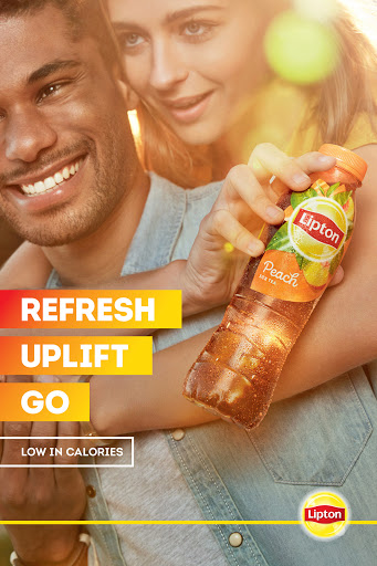An attractive couple smiles, holding a bottle of Lipton Peach Iced Tea in warm, inviting lighting for a beverage advertisement.