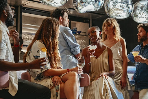 Group of friends enjoying cocktails in a modern bar setting with contemporary decor and stylish lighting, creating a vibrant social atmosphere.