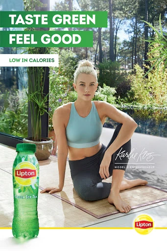Attractive woman in exercise clothing poses next to a bottle of Lipton Green Ice Tea in an outdoor wellness lifestyle setting.