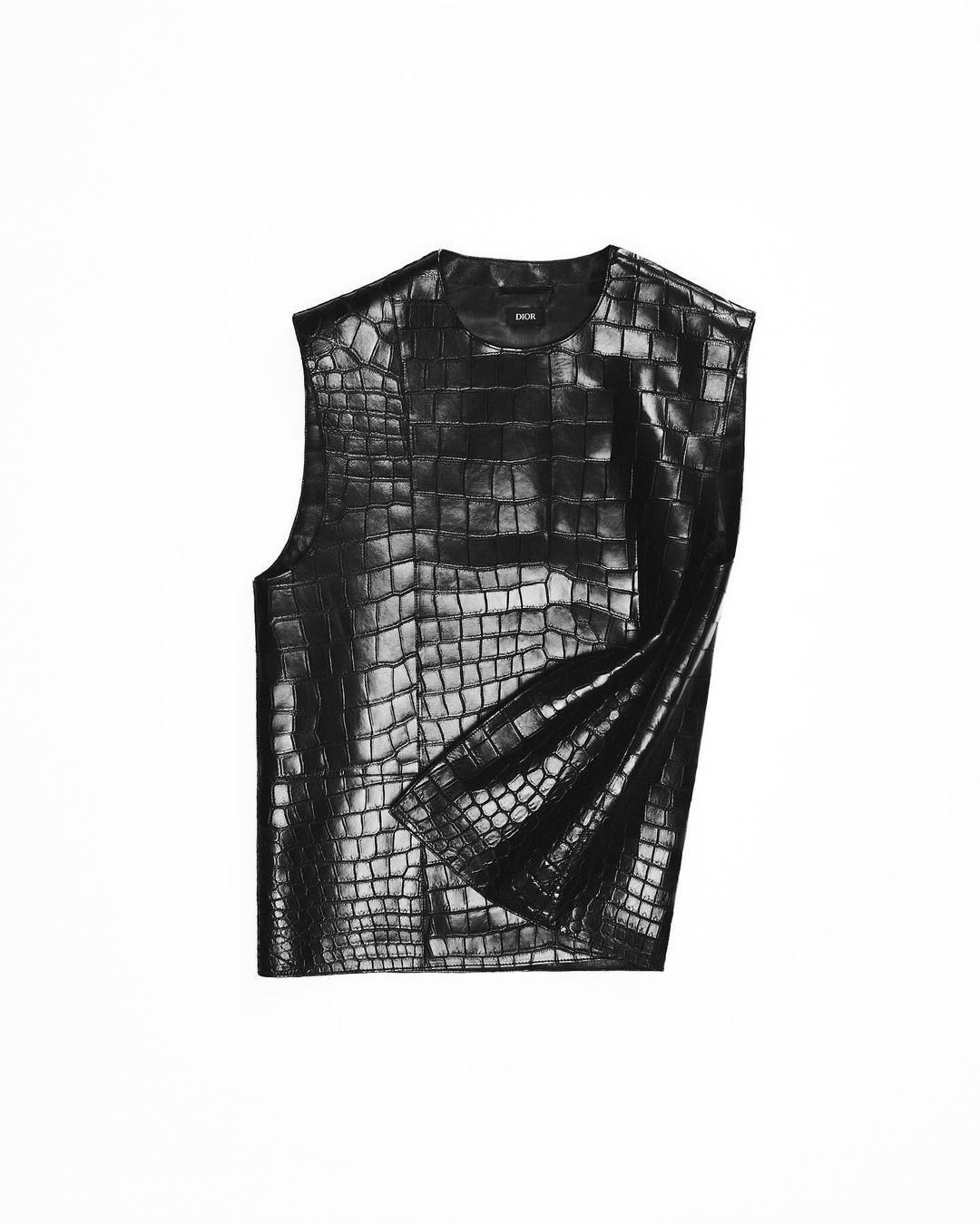 Sleeveless black top with a crocodile skin pattern isolated on a white background. Close-up studio shot of fashion clothing.