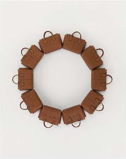 Circular arrangement of a dozen brown leather tote handbags. The design forms a complete circle against a plain white background.