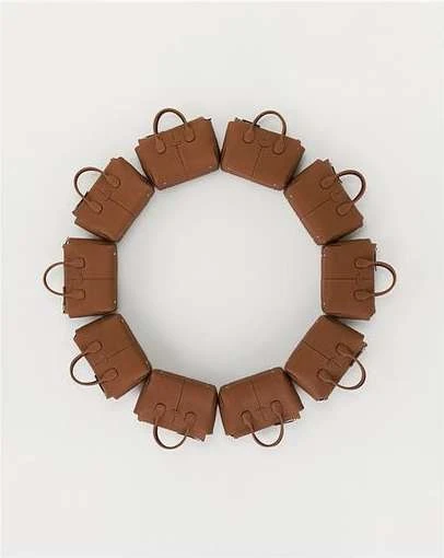 Circular arrangement of a dozen brown leather tote handbags. The design forms a complete circle against a plain white background.