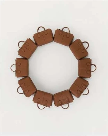 Circular arrangement of a dozen brown leather tote handbags. The design forms a complete circle against a plain white background.