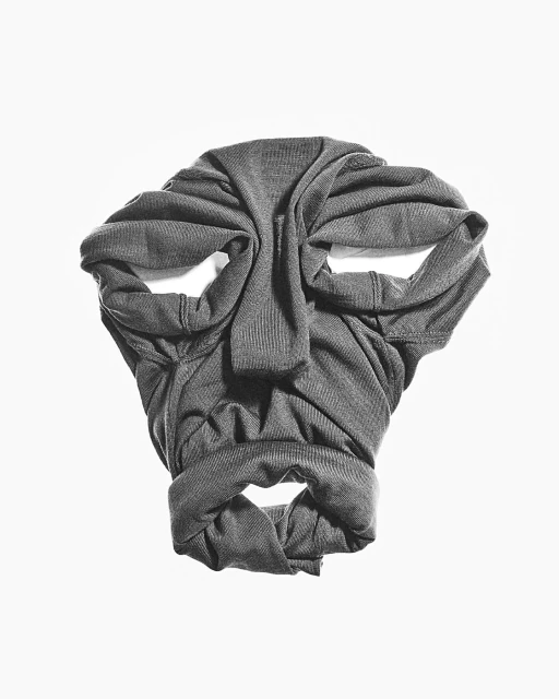 Folded gray shirt creates a face-like pattern on white background. Close-up studio shot of apparel artfully arranged to resemble features.