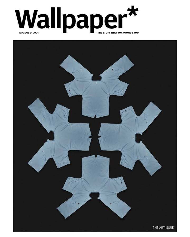 Wallpaper magazine cover featuring an artful arrangement of folded light blue t-shirts against a dark background.