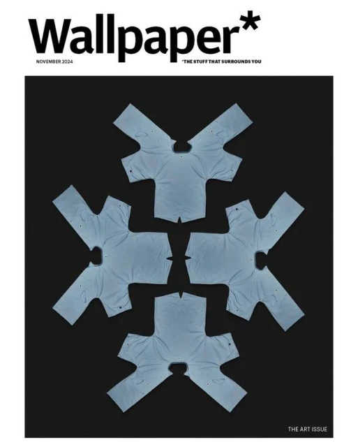 Wallpaper magazine cover featuring an artful arrangement of folded light blue t-shirts against a dark background.
