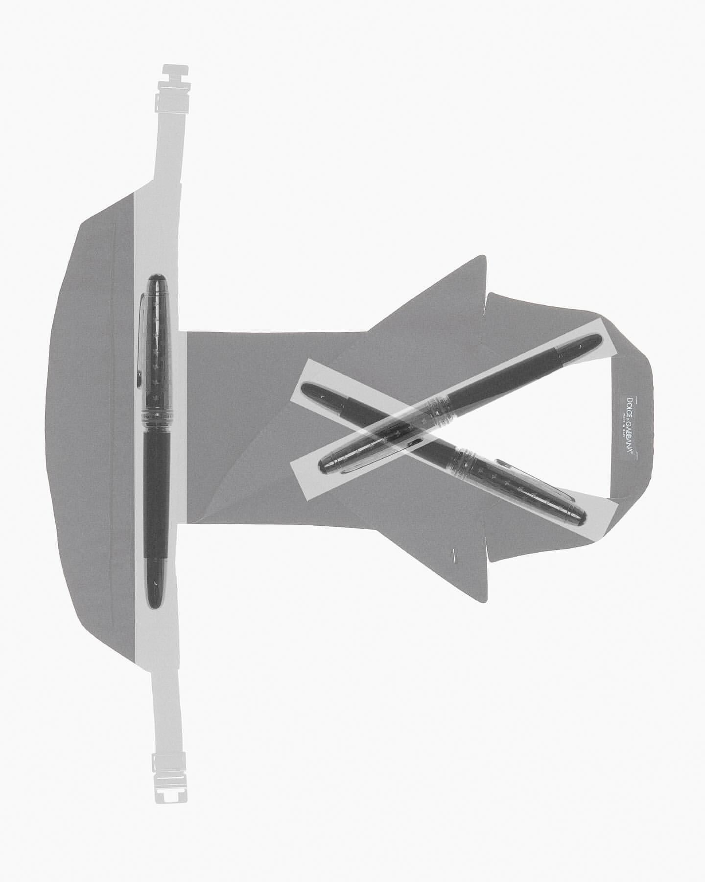 A gray stationery set features a stand with a fountain pen placed in it, plus two pens crossed and taped to a blank card.