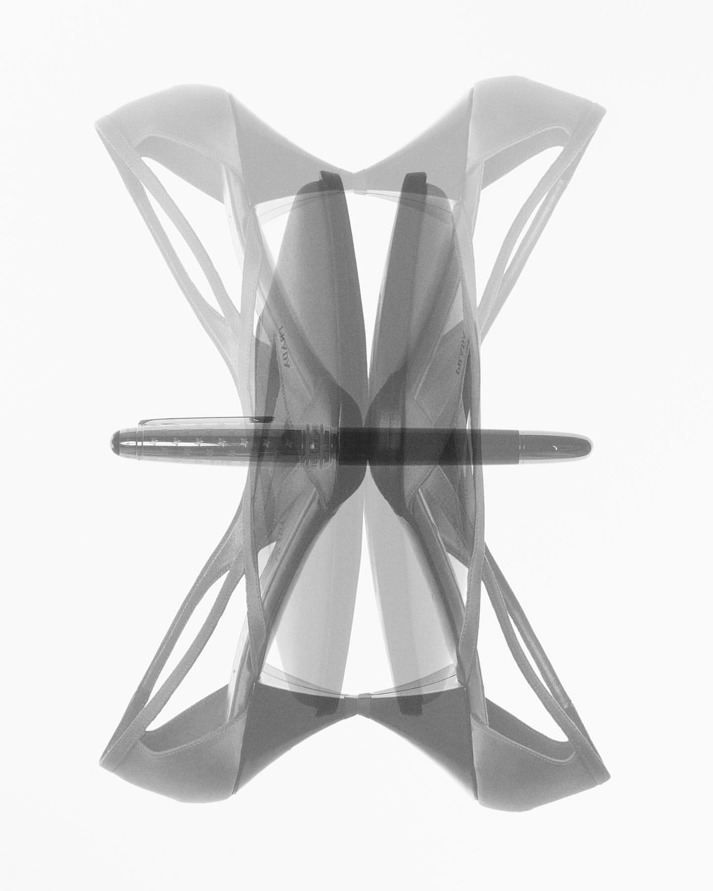 Ghosted image of high heels and a fountain pen on a bright white background with a stark contrast, creating a modern abstract composition.