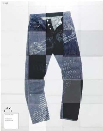 Studio shot of blue denim jeans with button fly and abstract patterning, presented on a white surface with a square grid backdrop.